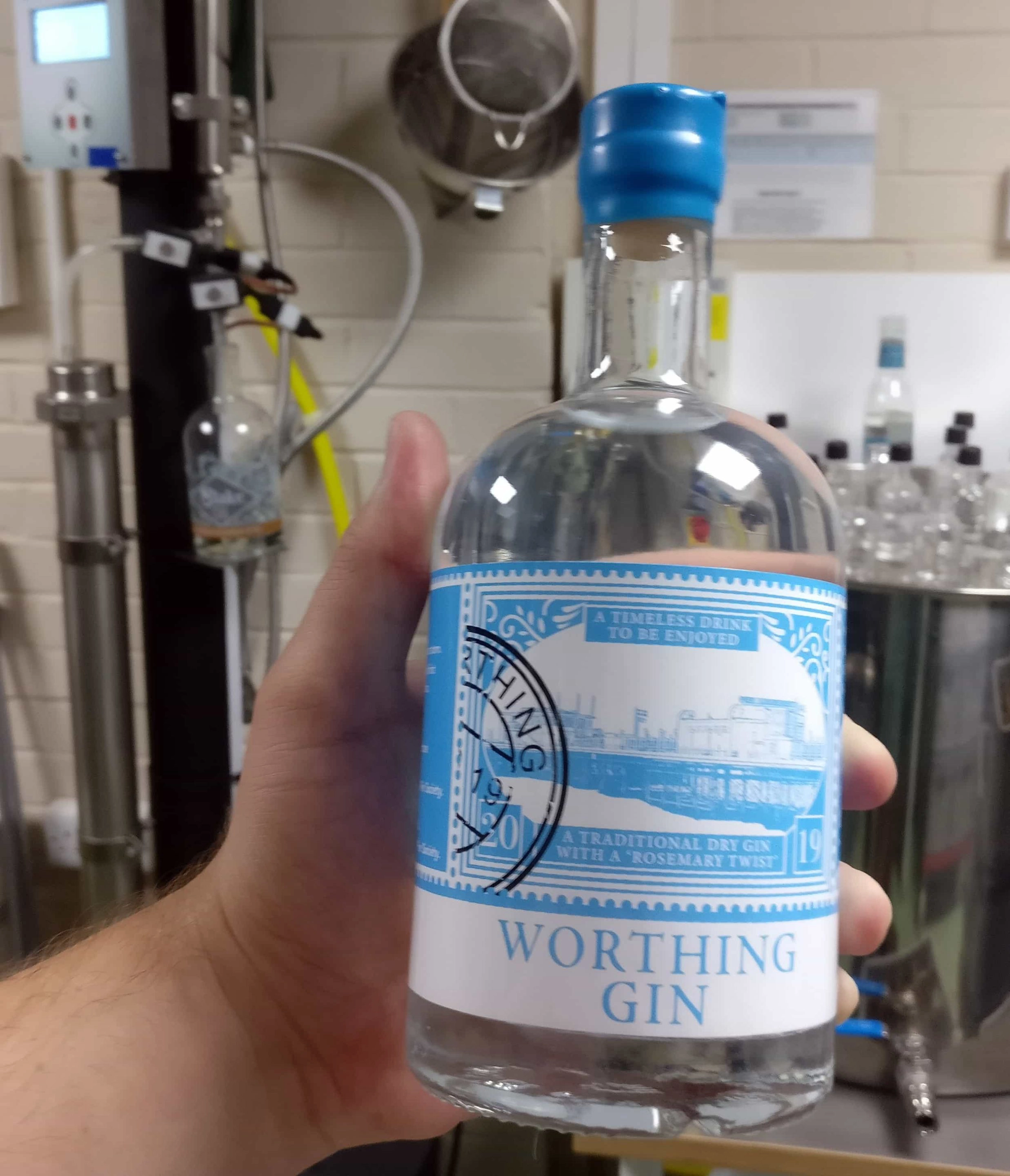 Tom holding a bottle of Worthing Gin in the distillery where it is made at Slake Spirits