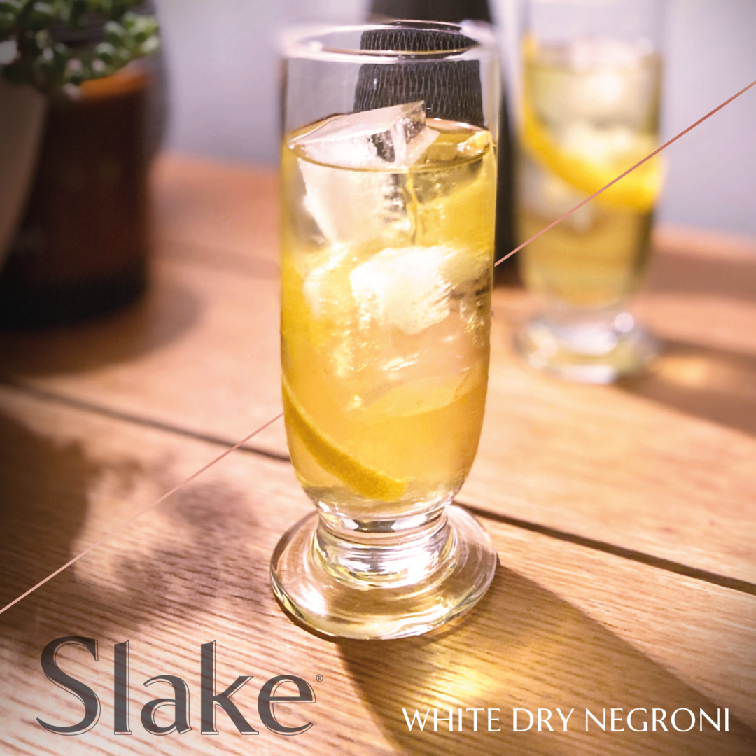 White Negroni served in a tall shot glass garnished with a lemon twist