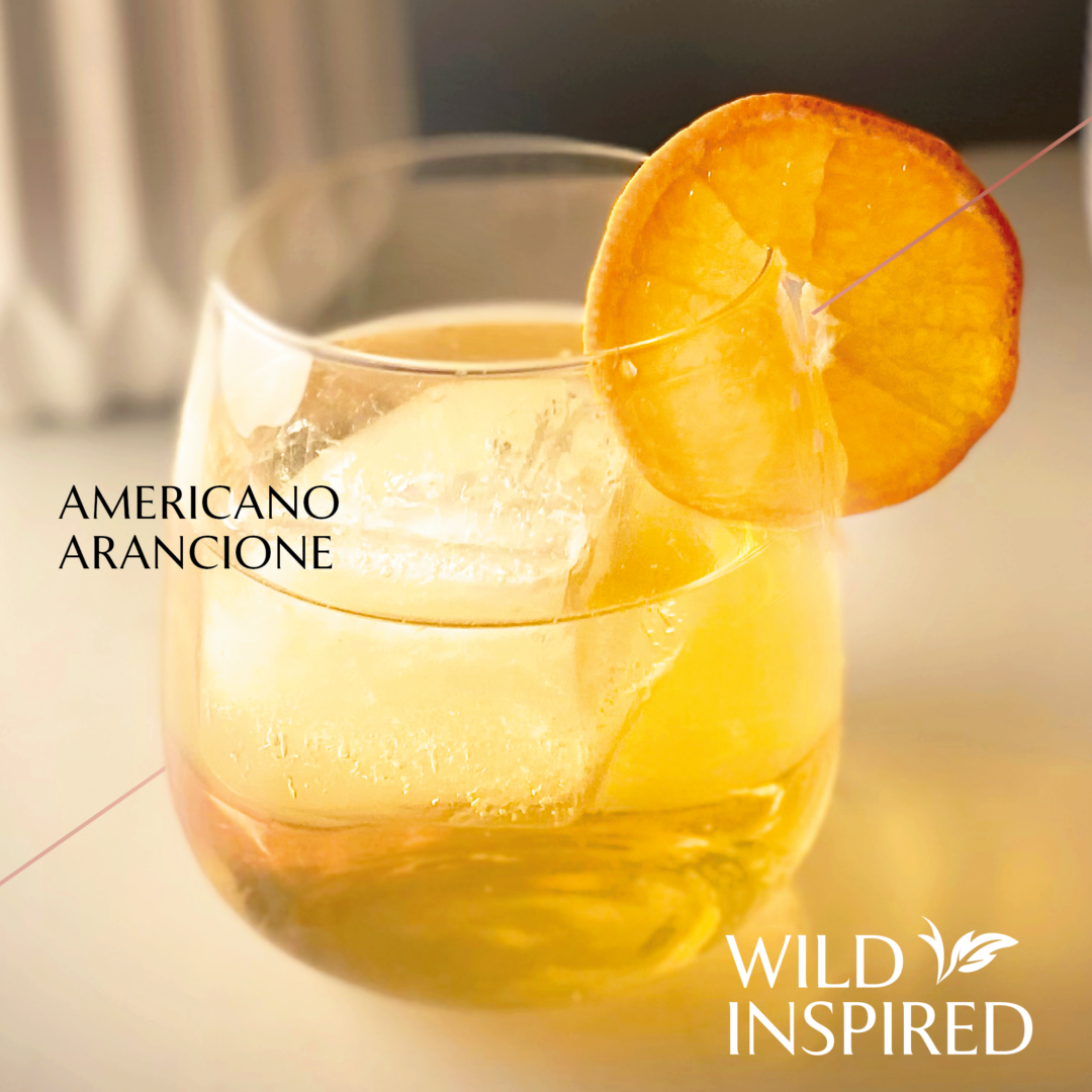 Gin & amaro topped with tonic water served in a large stemless wine glass garnished with an orange wheel